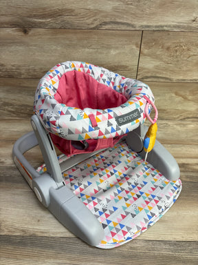 Colorful baby floor seat with geometric triangle print and pink padded interior on wooden background