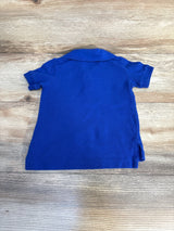 Back view of a blue short sleeve kids polo shirt on wood background