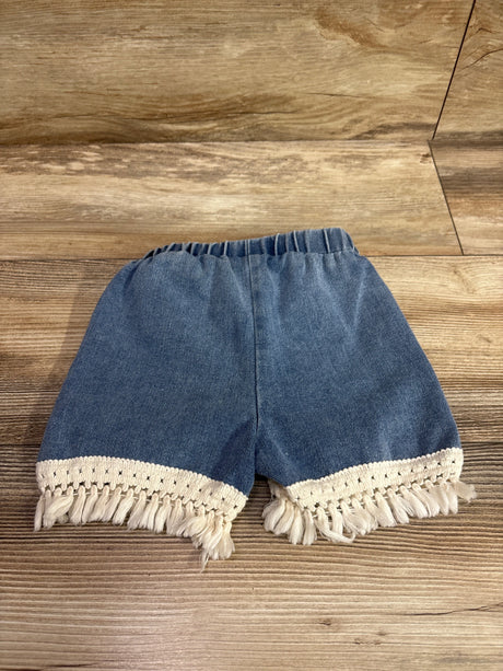 Blue pull-on denim shorts for toddlers with cream tassel trim hem on a wooden background