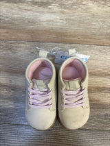 Beige baby shoes with pink laces on wood floor, gently used toddler footwear