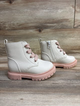 Pair of white toddler boots with pink soles and laces on a wooden floor background