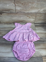 Flat lay of pink Carter's two-piece floral dress and bloomers showcasing ruffled tiered skirt and elastic waist on wood floor background