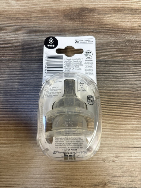 Packaged baby bottle nipples, flow 4, clear silicone, on wood background
