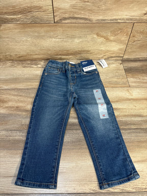 Front view of Old Navy toddler skinny jeans size 2T showing faded wash, attached tags, and size stickers on wood floor background