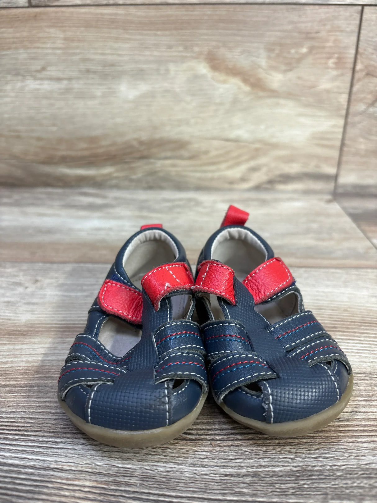 Front view of navy See Kai Run Fisherman toddler sandals size 3C showcasing red Velcro straps and textured toe on wood background