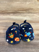 Front view of baby navy plush slippers showcasing colorful rocket and planet print with wooden tabletop background