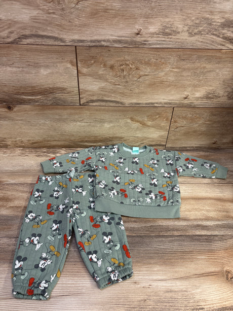 Top-down view of green Disney Baby Mickey Mouse sweatshirt and joggers set, size 9 months, with all-over print on wood floor