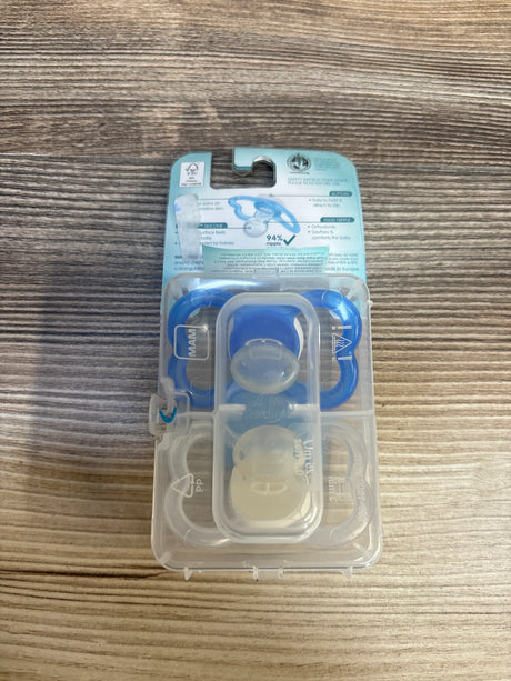 MAM blue and white silicone baby pacifiers in plastic case on wood surface