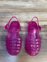 Top down view of Janie and Jack pink jelly fisherman sandals size 9C showing translucent strappy upper and ankle buckle on wood floor