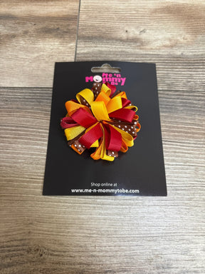 Colorful hair bow with red, yellow, and brown ribbons on Me 'n Mommy Be display card