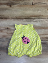 Flat lay of baby shortie romper showing lime yellow fabric with white polka dots and pink ladybug applique on wood background