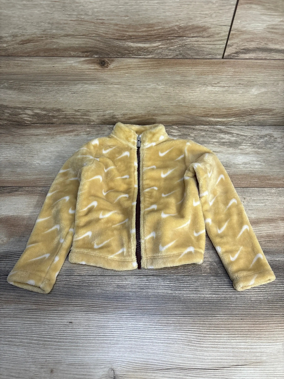 Yellow kids fleece jacket with white swoosh pattern, full zip, laid on wood floor
