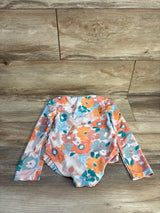 Flat-lay of multicolor watercolor floral long-sleeve rashguard swimsuit size 4T showcasing full front on wood background