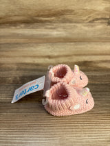 Pink knitted unicorn baby booties with Carter's tag on wooden surface