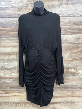 Black ruched maternity long sleeve dress with mock neck on hanger, wood background