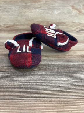 Red and navy plaid baby crib shoes with white text and faux fur trim on wooden background