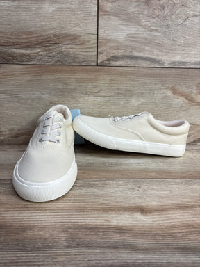 Beige canvas toddler sneakers with white rubber soles on wooden background