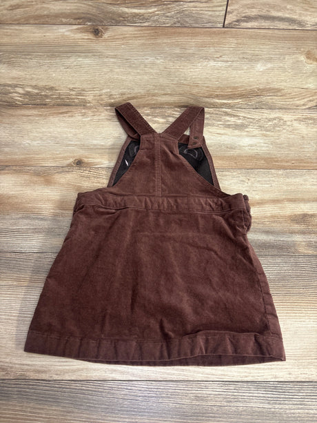 Brown corduroy toddler pinafore dress with adjustable straps on wooden floor