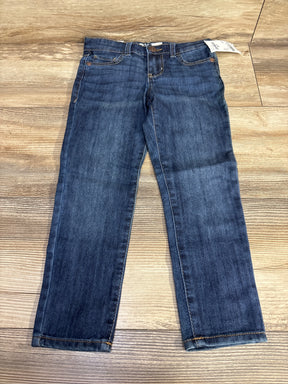 Kids blue denim jeans with front pockets and button, displayed on wood floor