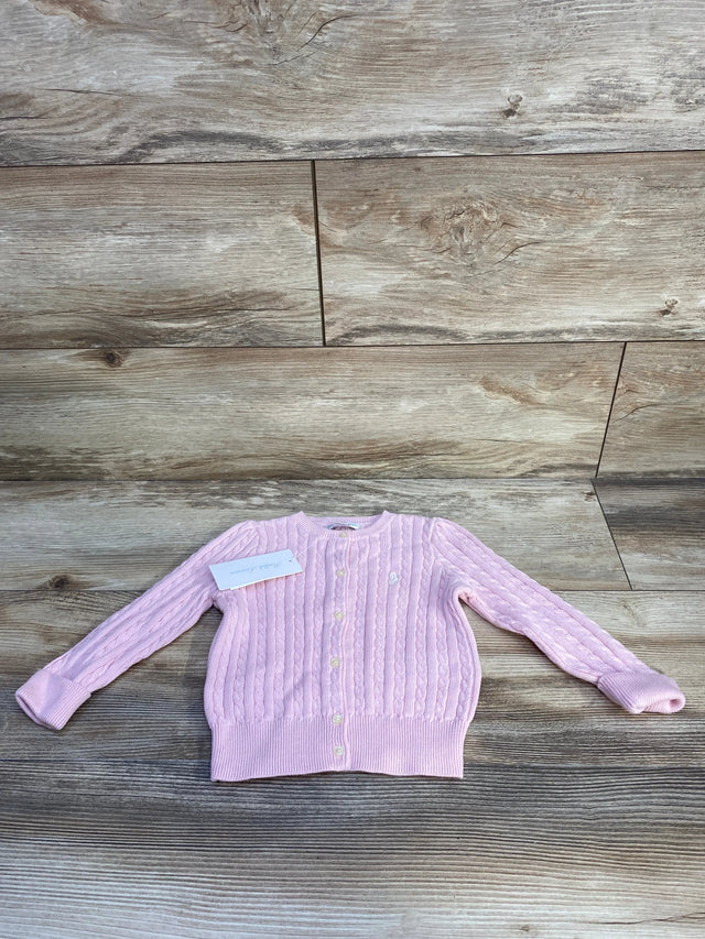 Front view of Ralph Lauren cable-knit baby cardigan showing button-front closure, embroidered pony logo, and ribbed cuffs in light pink on wood background