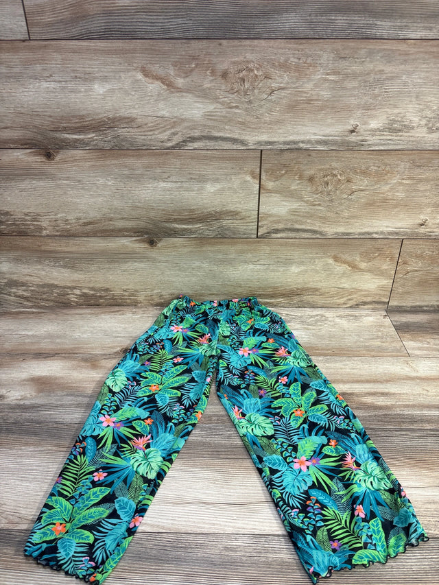 Flat lay of teal tropical print swim cover up pants showing elastic waistband and ruffled ankle hems on wood background
