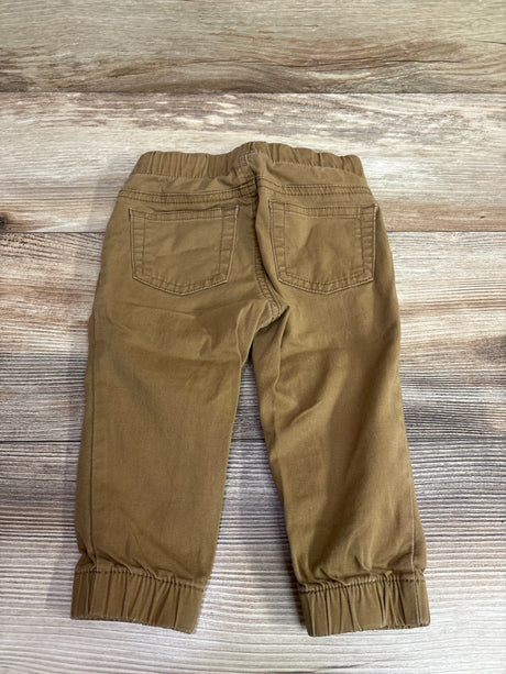 Rear view of tan Cat & Jack cotton joggers for infants on a wood background.
