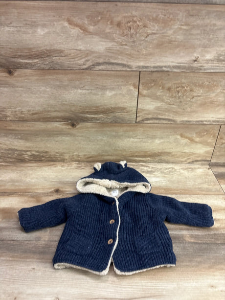 Front view of Baby Gap navy lined knit bear cardigan with cream trim, bear-ear hood, and button front on wood backdrop