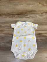 Flat-lay of white baby bodysuit showcasing yellow sun and rainbow print with three-snap crotch on wood background