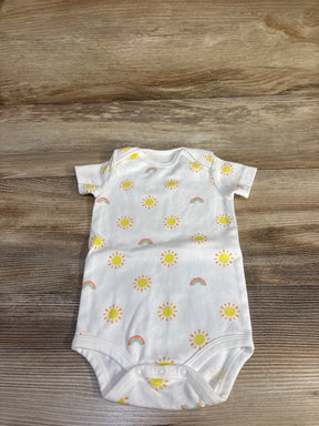 Flat-lay of white baby bodysuit showcasing yellow sun and rainbow print with three-snap crotch on wood background