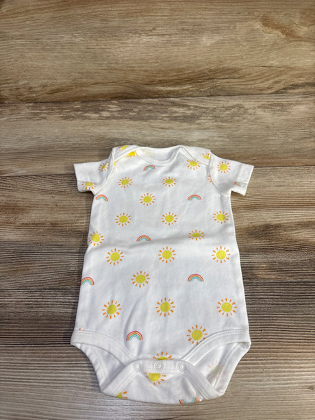 Flat-lay of white baby bodysuit showcasing yellow sun and rainbow print with three-snap crotch on wood background