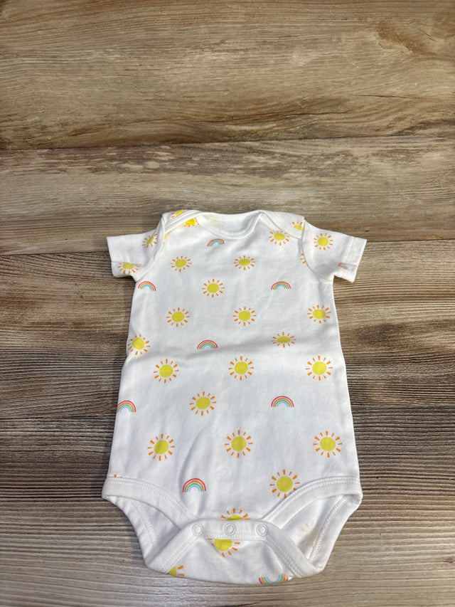 Flat-lay of white baby bodysuit showcasing yellow sun and rainbow print with three-snap crotch on wood background