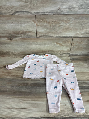 Flat lay of pink 2-piece pajama set showing long-sleeve top and leggings with multicolor vehicle print on wood background
