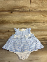 Flat-lay of blue and white striped baby bodysuit dress showcasing ruffle cap sleeves, two front bows, gathered skirt and snap-closure crotch on wood background