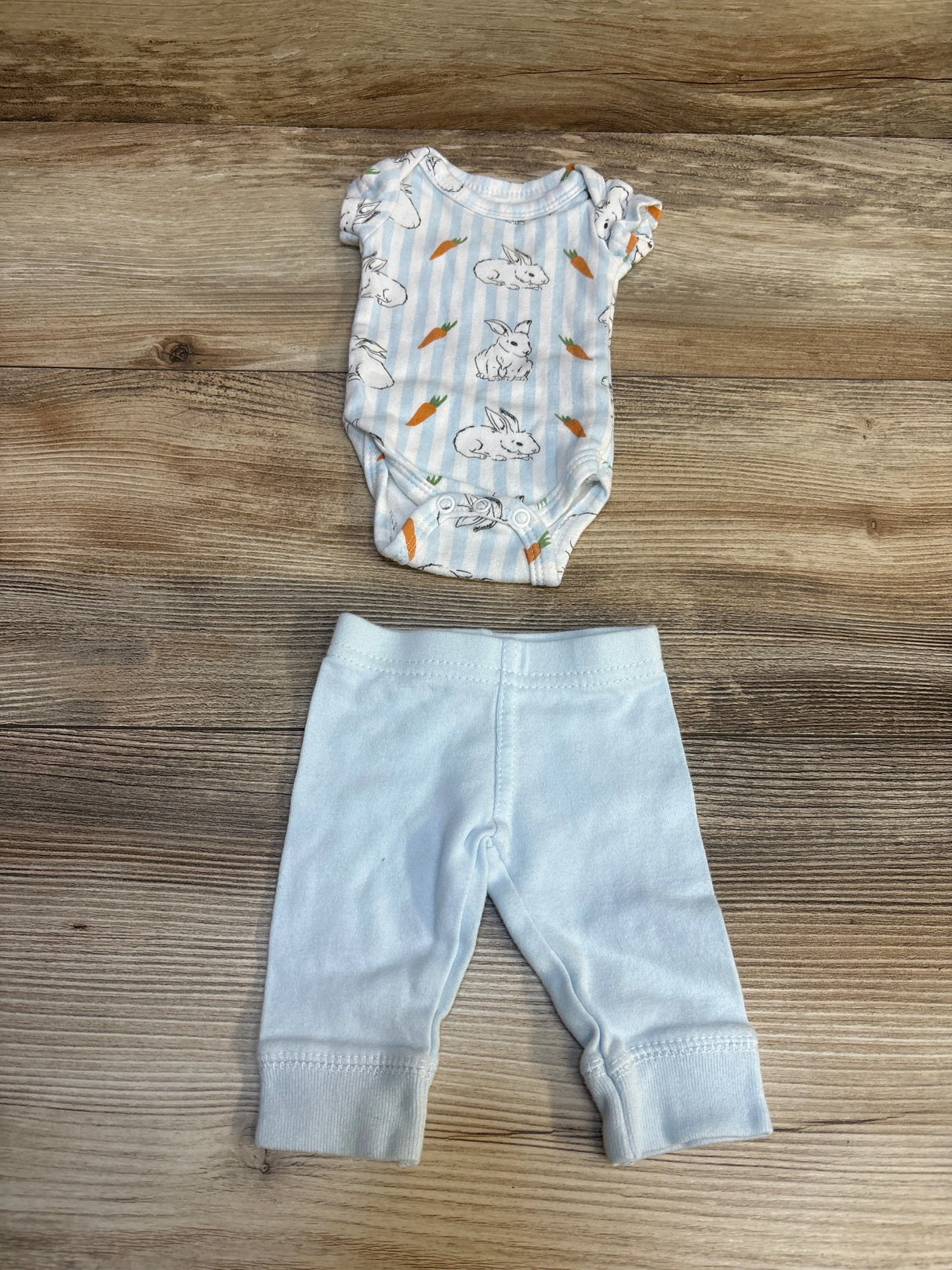 Baby bunny and carrot print onesie with light blue pants, soft infant clothing set on wood floor
