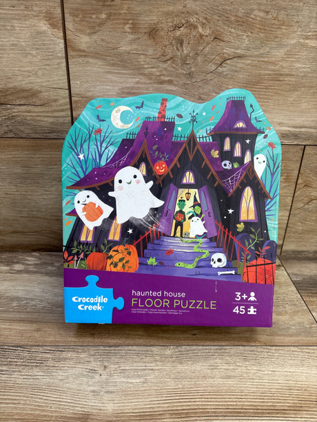 Front view of Crocodile Creek Haunted House Floor Puzzle packaging showing haunted house artwork, 45 pieces, on wood flooring