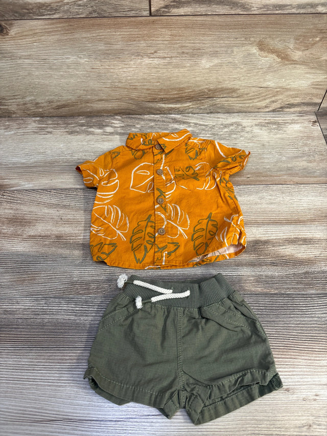 Flat lay of newborn orange button-up shirt and olive green shorts showing wooden buttons on wood background