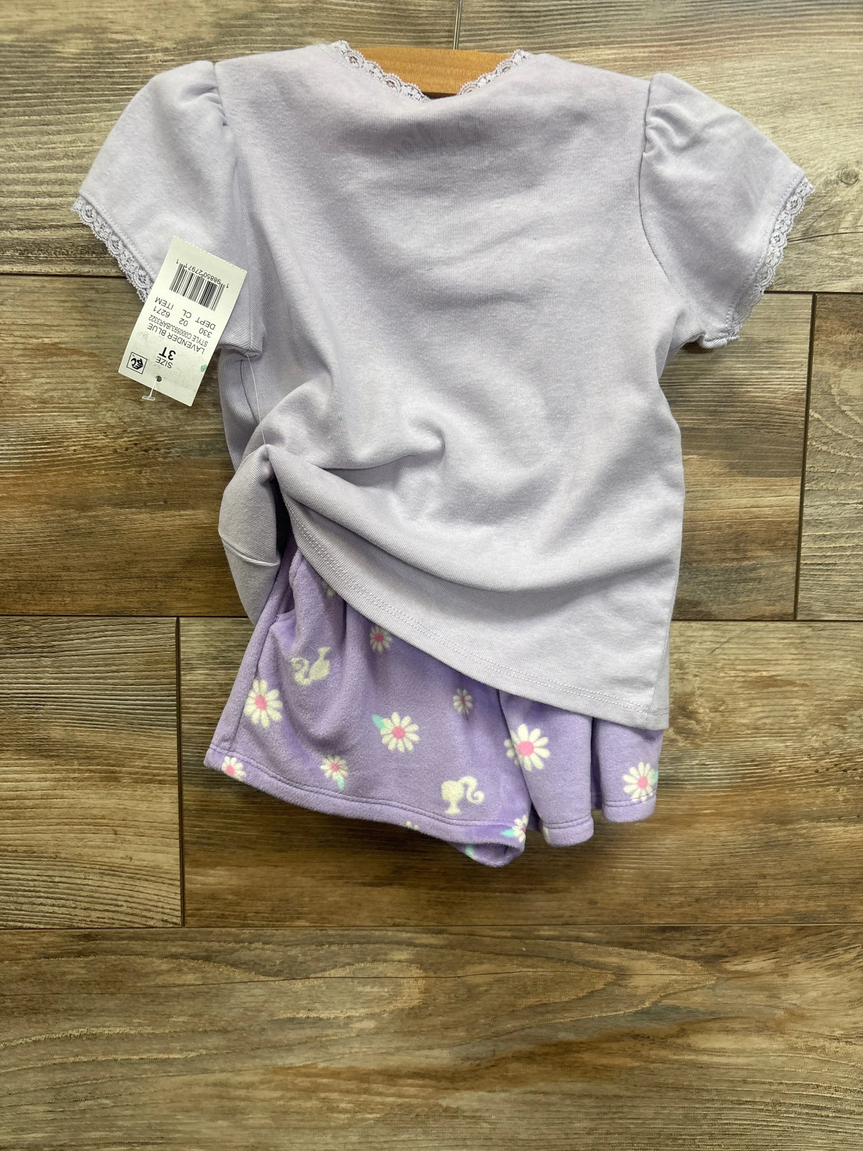 Lavender short sleeve toddler pajama set with lace trim and floral shorts on wood floor