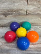 Front view of six balls from Lakeshore Learning ball toss set showing bright colors and glossy finish on light wood floor