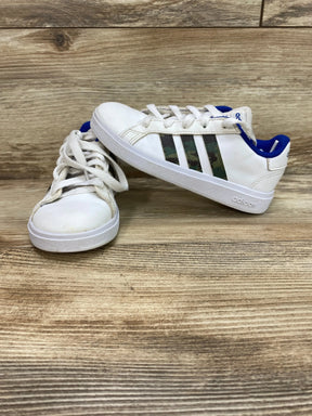 Side and front view of Adidas Grand Court Base kids shoe, white with camo stripes and royal blue lining on wood background