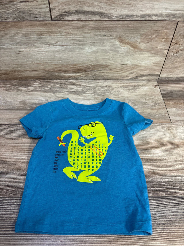 Flat lay of blue toddler Cat & Jack short-sleeve shirt showing yellow dinosaur word-find graphic on wood floor background