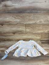Long sleeve pastel tie-dye toddler shirt with ruffled hem on wooden background