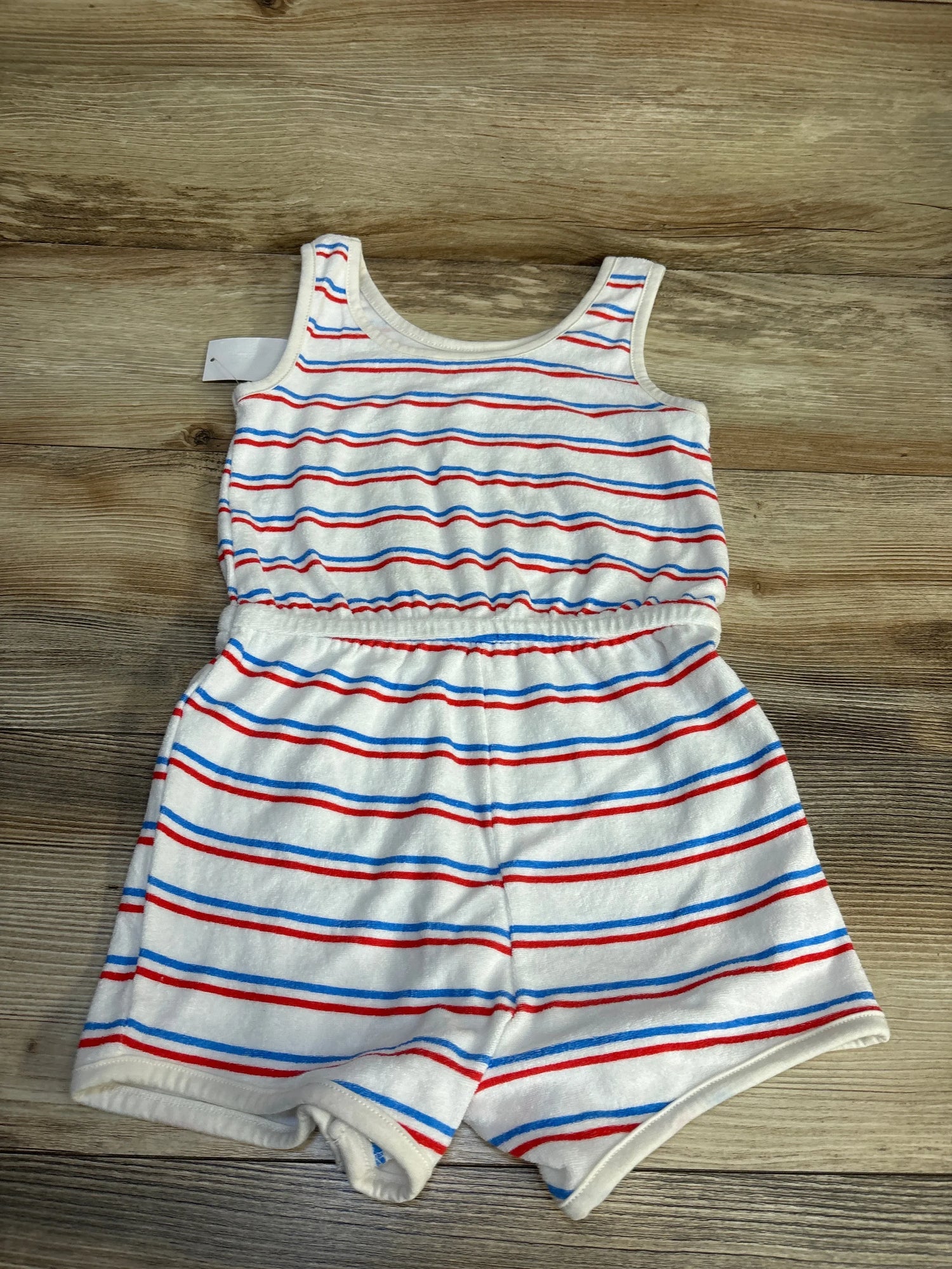 Sleeveless toddler romper with red, blue, and white stripes on wooden background