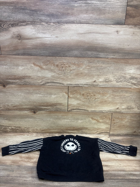 Front view of The Nightmare Before Christmas black pullover sweatshirt in size 3T showcasing white striped sleeves and skull graphic on wood flooring