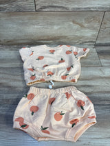 Top-down view of Jessica Simpson 2pc shirt and shorts set, size 3-6M, peach with peach print and elastic waists on wood
