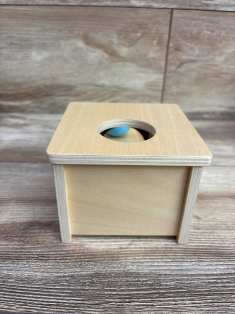 Front view of Adena Montessori Wooden Object Permanence Box showcasing round top opening and blue ball inside with wood-grain background