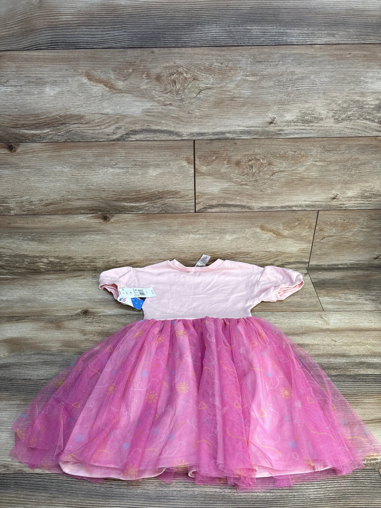 Pink short sleeve toddler dress with tulle skirt and floral patterns on wooden floor