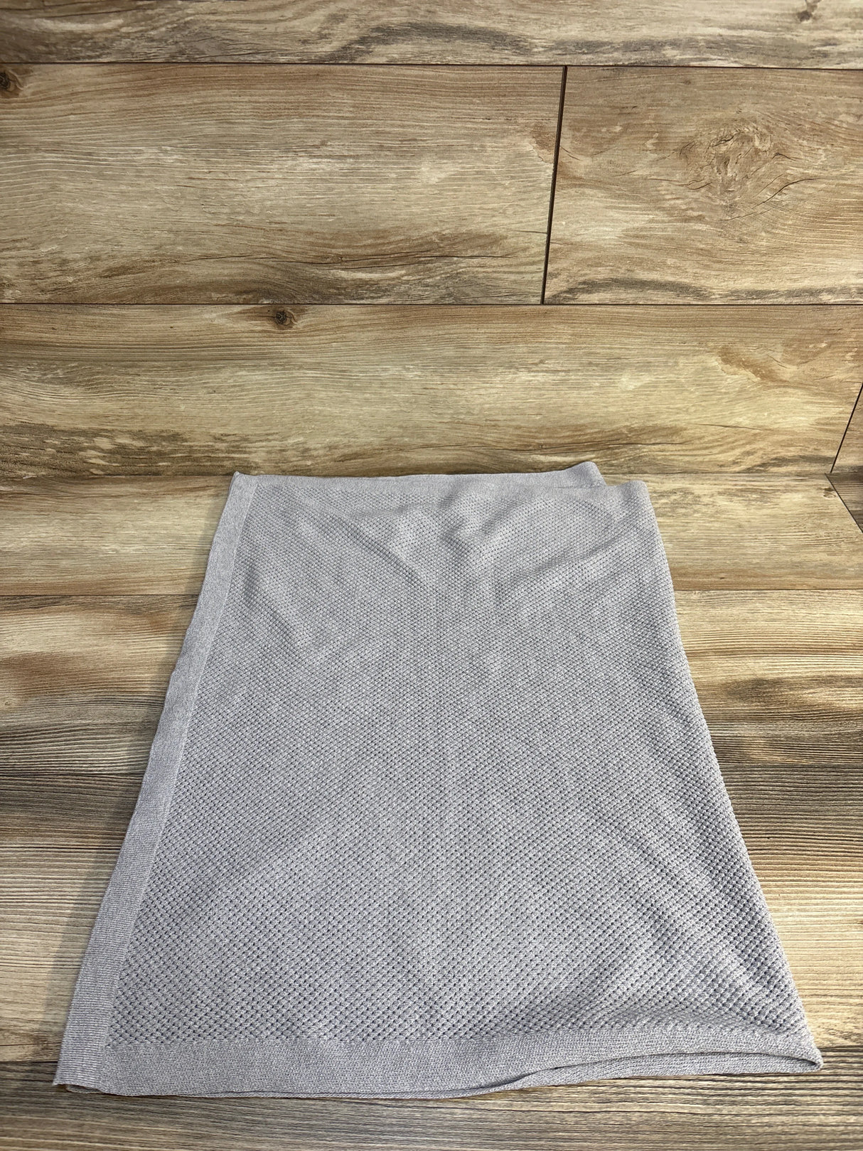 Light gray knit baby blanket displayed on wooden surface