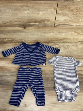 Striped navy blue baby cardigan and pants set next to short-sleeve white and navy striped onesie on wooden background