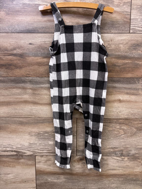 Black and white buffalo checkered baby romper hanging on wooden hanger on wood floor background