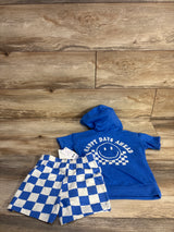 Flat lay of blue toddler two-piece set with 'Happy Days Ahead' smiley on hooded tee and blue-and-white check shorts on wood backdrop